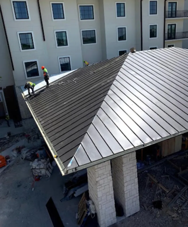 Crew installing standing seam metal roof panels on a commercial project in Ware